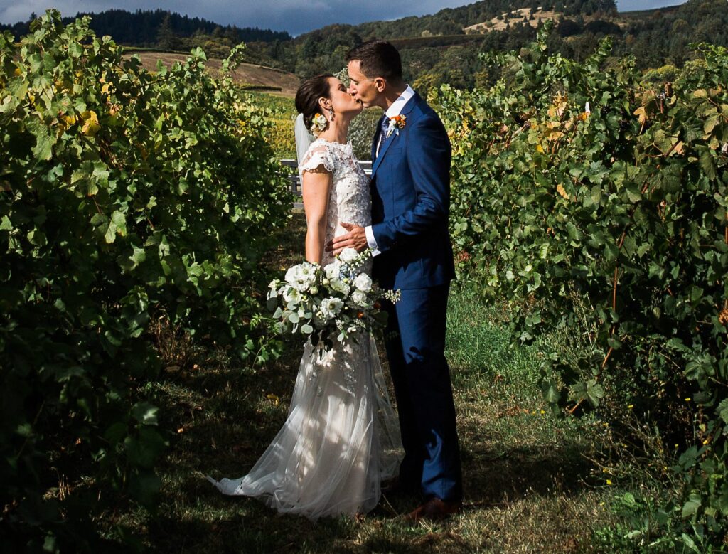 bride and groom kissing in vineyard
