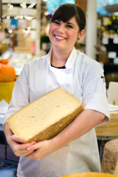 a chef holding a giant half wheel of cheese