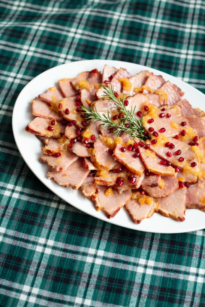 applewood smoked ham on a white serving dish on a green plaid tablecloth